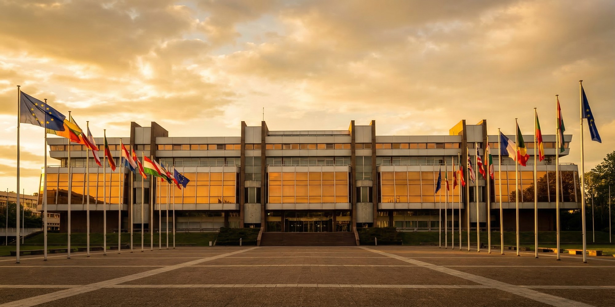 The Palais de l'Europe in Strasbourg at golden hour, European flags arranged in a semicircle before the Council of Europe building