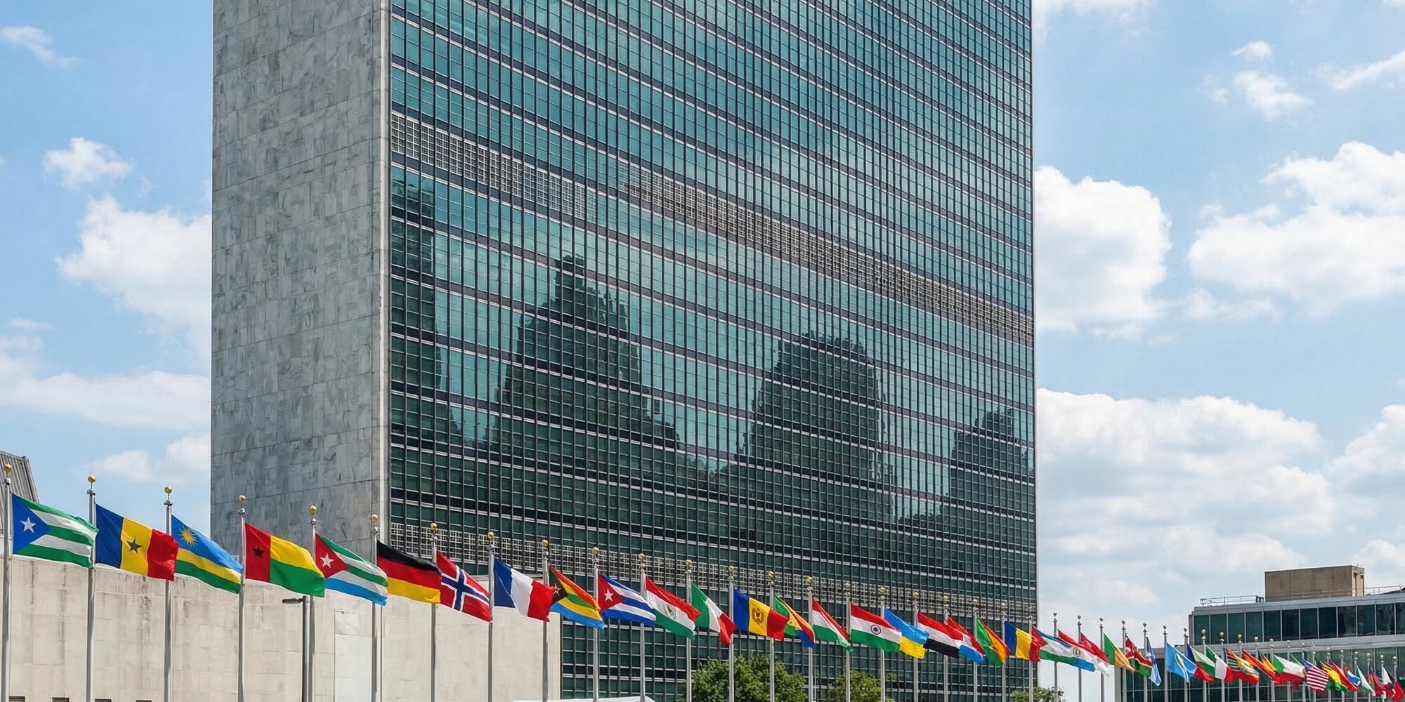 United Nations headquarters building with international flags on flagpoles against a blue sky